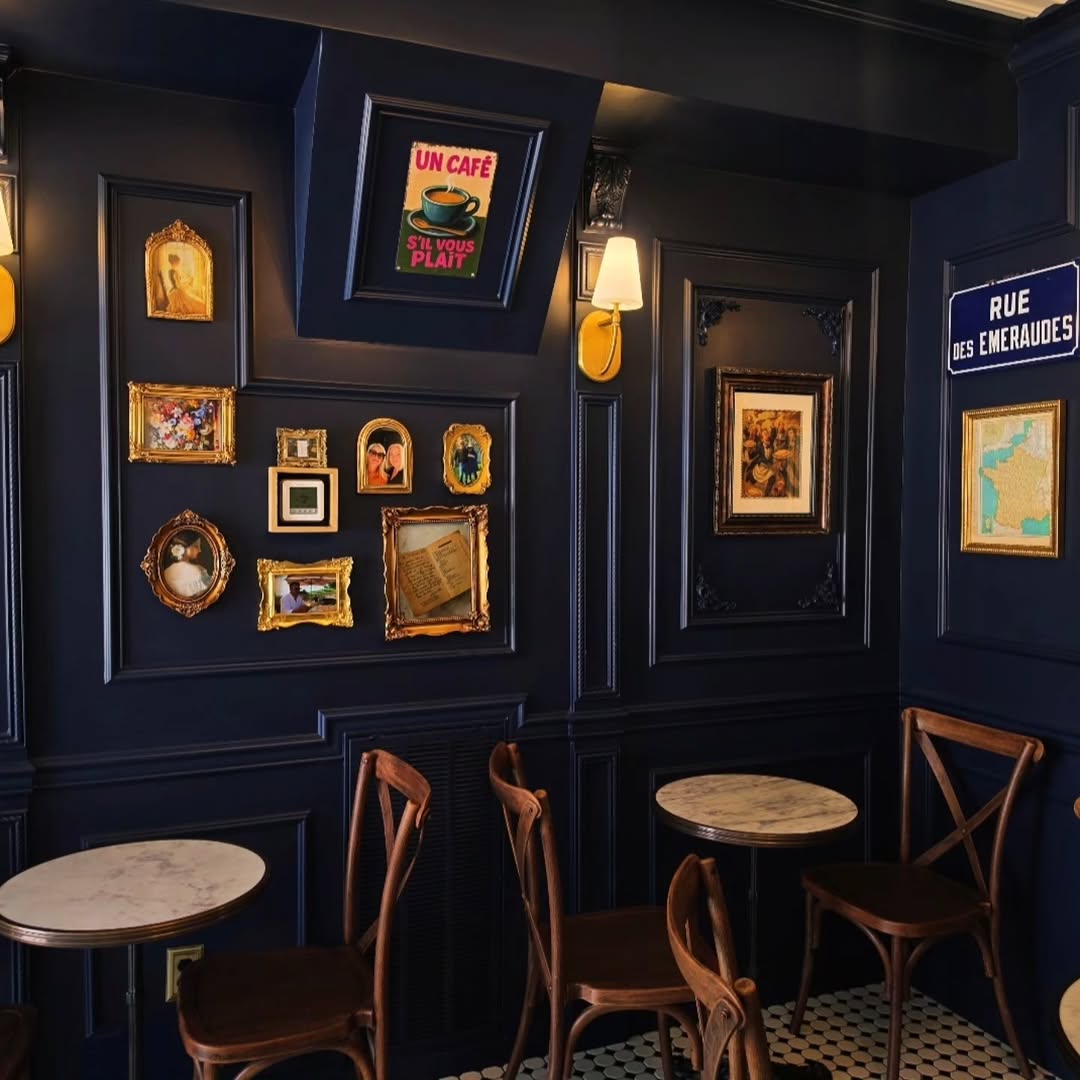 The navy-walled dining room at Maminette in Donelson, with marble cafe tables and framed family pictures
