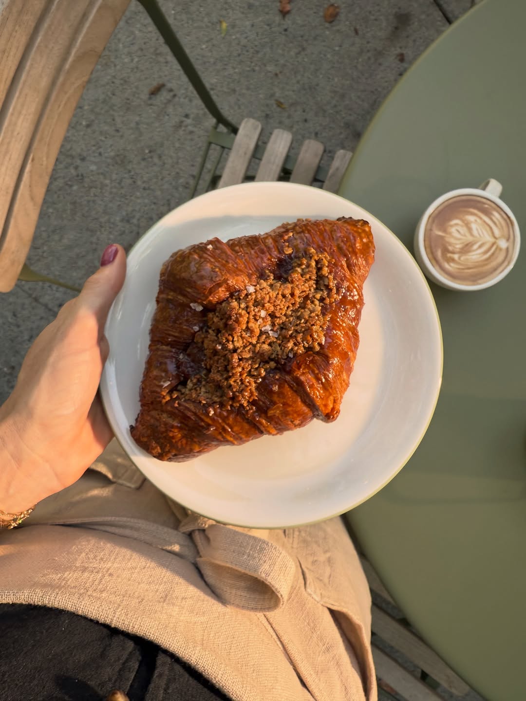 Perenn's Twice Baked Caramel Apple Pie Croissant on a plate, with a latte