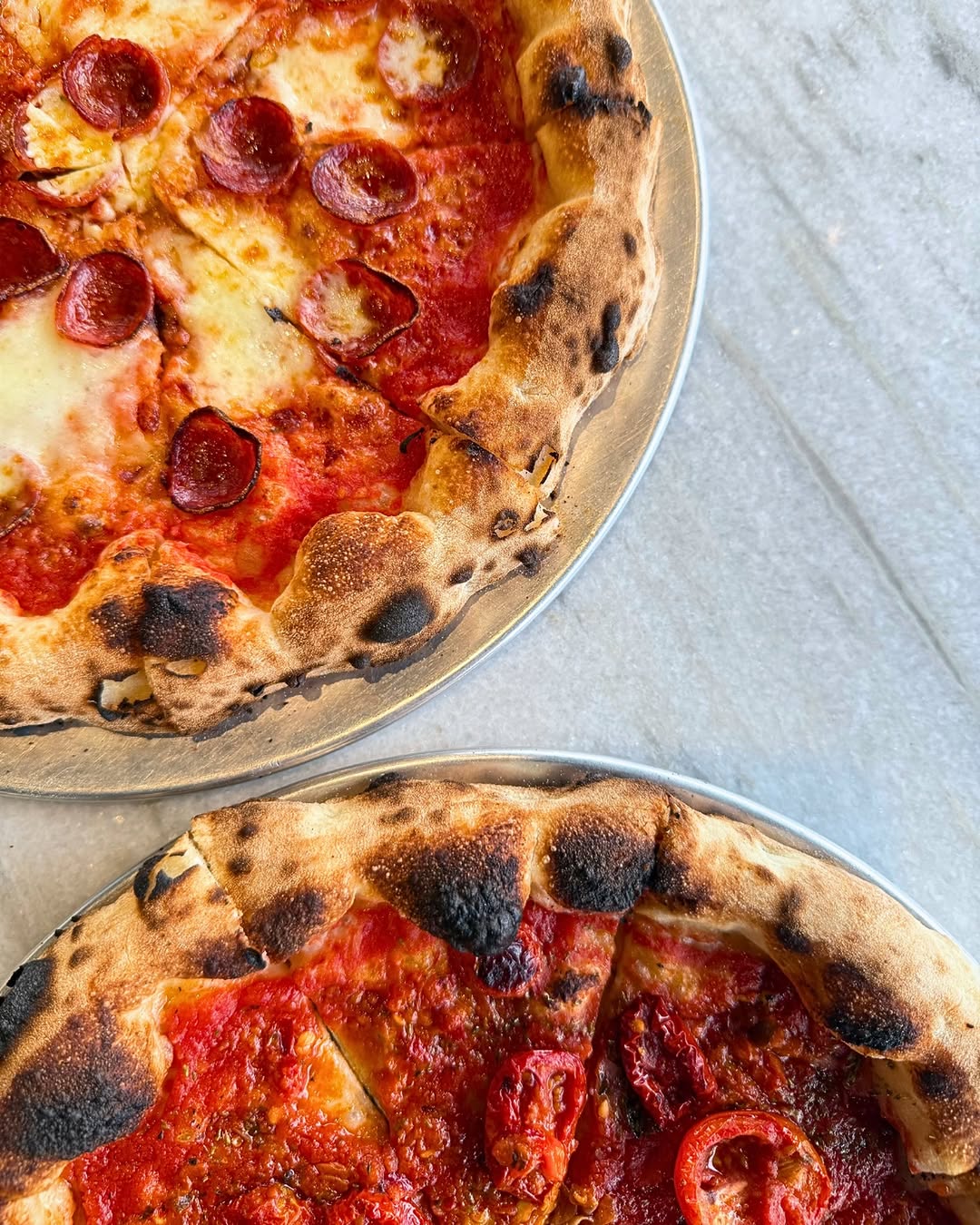 Two wood-fired pizzas at Sho Pizza Bar, with blistered, charred crusts