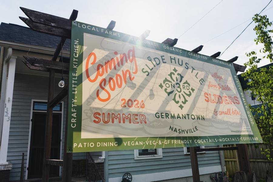 The Slide Hustle on 3rd coming-soon banner in front of the restored Germantown cottage